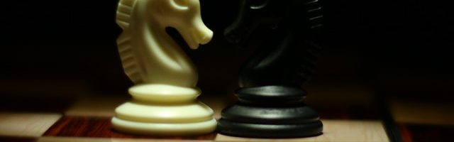 Two white and black chess knights facing each other on chess 839428 640x200