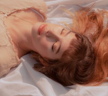 Woman with eyes closed lying on white textile 3960803 360x320