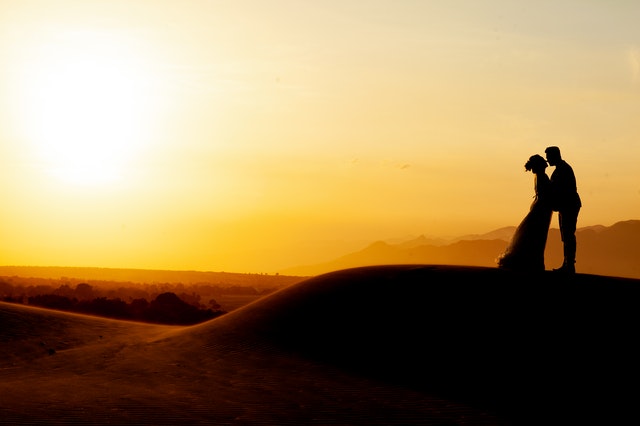 Silhouette of man and woman standing on rock formation 3998368