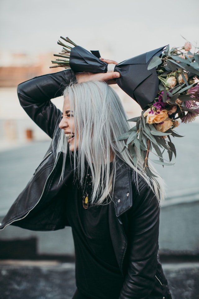 Woman wearing black leather jacket holding flower bouquet 1035677