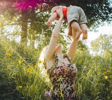 Woman carrying baby near grass 1261909 360x320