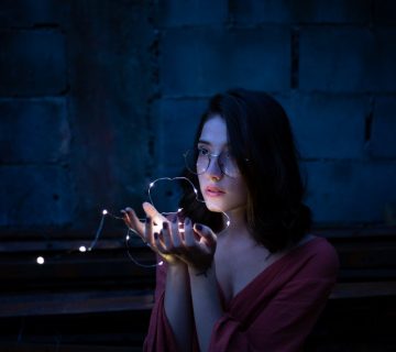 Woman wearing red dress holding turned on string lights 1854129 360x320