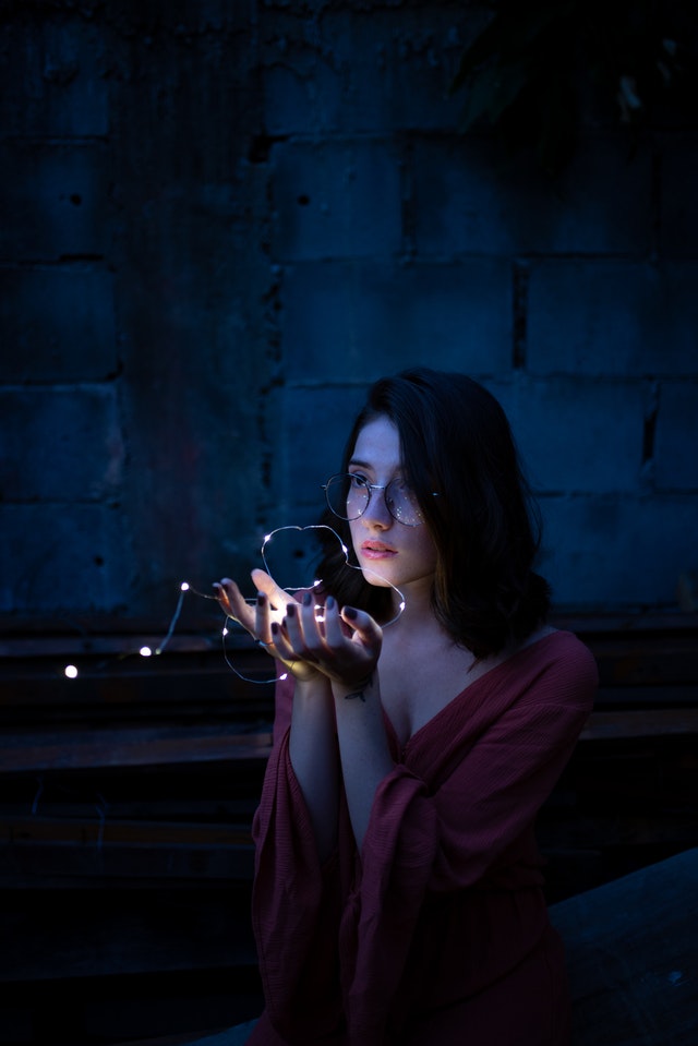 Woman wearing red dress holding turned on string lights 1854129